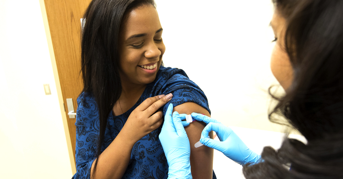 Nurse applies bandaid to woman after she receives her COVID-19 vaccine